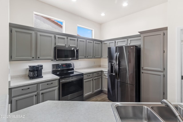 kitchen featuring dark wood-style flooring, light countertops, appliances with stainless steel finishes, a sink, and gray cabinets