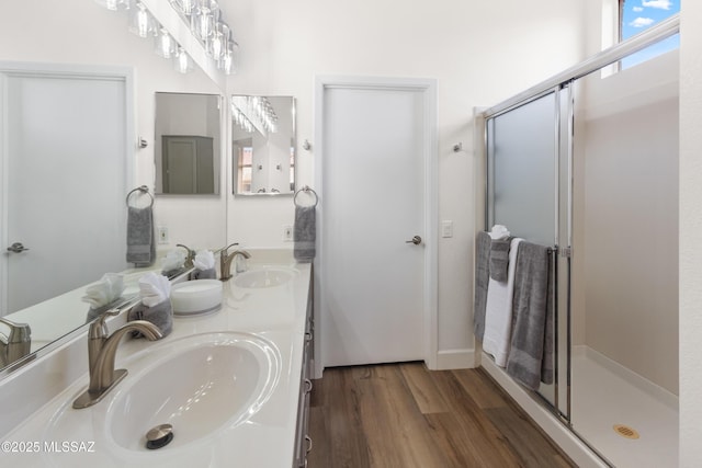 full bath featuring a stall shower, double vanity, wood finished floors, and a sink