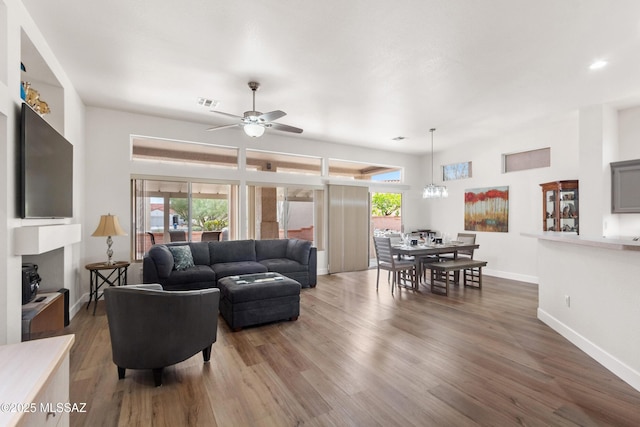 living area with baseboards, visible vents, wood finished floors, and ceiling fan