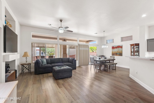 living room with a ceiling fan, visible vents, baseboards, and wood finished floors