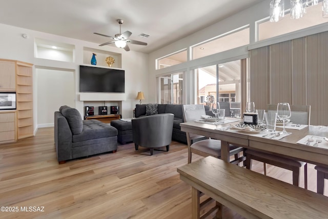 living area featuring visible vents, light wood-style flooring, and a ceiling fan
