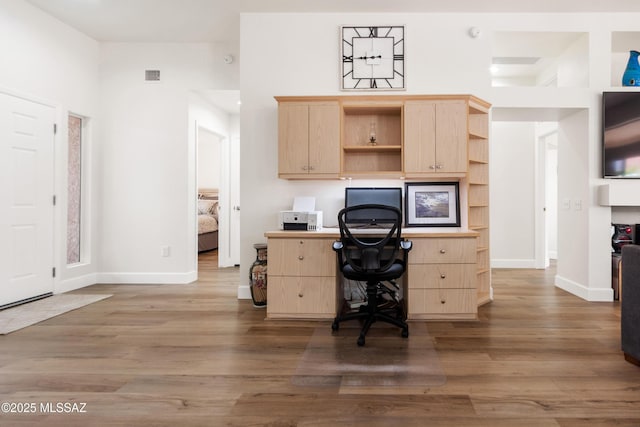 office area featuring baseboards, visible vents, wood finished floors, and built in study area