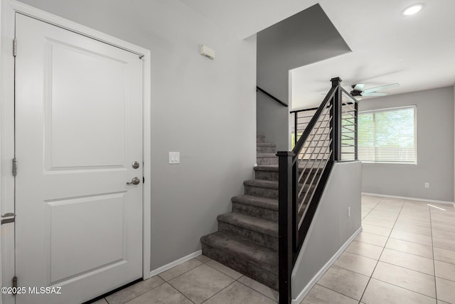 stairs featuring tile patterned floors, a ceiling fan, and baseboards