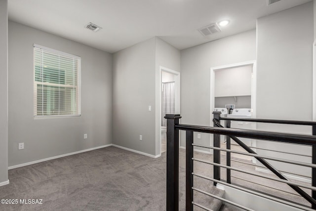 hall with carpet flooring, visible vents, an upstairs landing, and baseboards