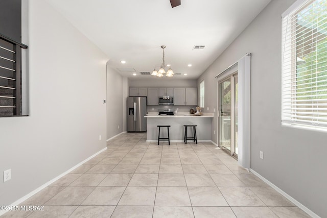 kitchen featuring visible vents, gray cabinets, appliances with stainless steel finishes, light countertops, and a notable chandelier