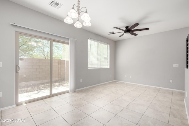 spare room featuring light tile patterned flooring, visible vents, a wealth of natural light, and ceiling fan with notable chandelier