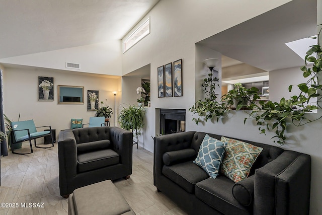 living room with wood tiled floor, high vaulted ceiling, a fireplace, and visible vents