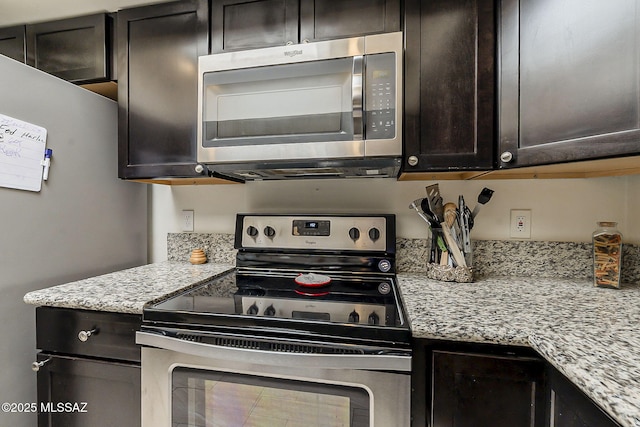 kitchen with dark brown cabinetry, light stone countertops, and appliances with stainless steel finishes