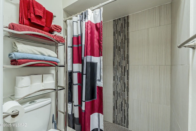 bathroom featuring a tile shower and toilet