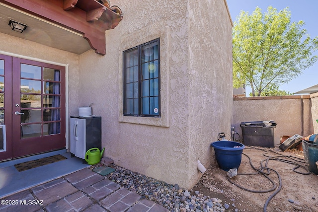 property entrance featuring stucco siding and fence