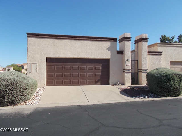 view of front of home with a garage, driveway, a chimney, and stucco siding