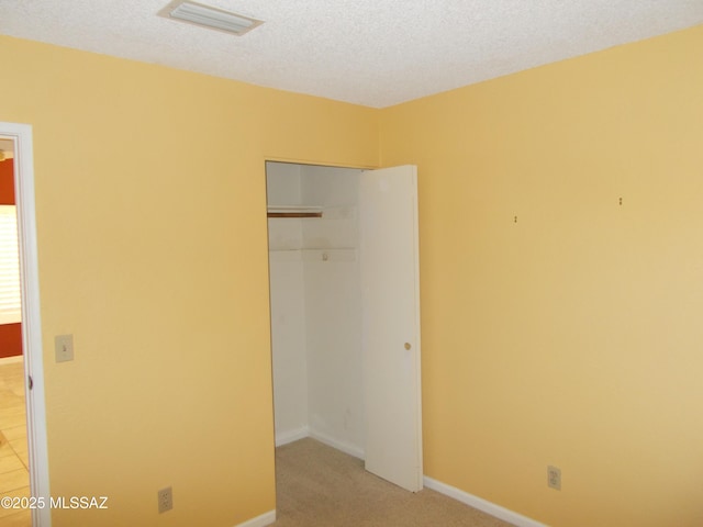 unfurnished bedroom featuring a closet, baseboards, visible vents, and a textured ceiling
