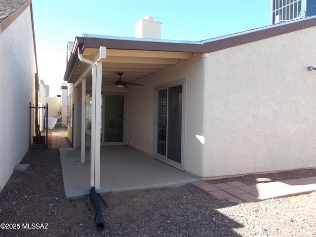 back of house with stucco siding, a chimney, a patio area, and ceiling fan