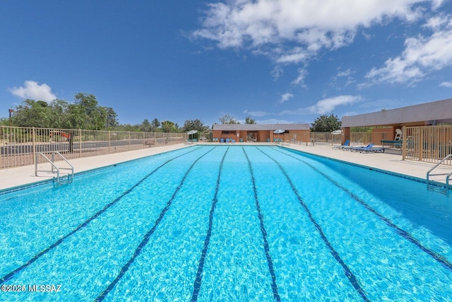pool with a patio area and fence