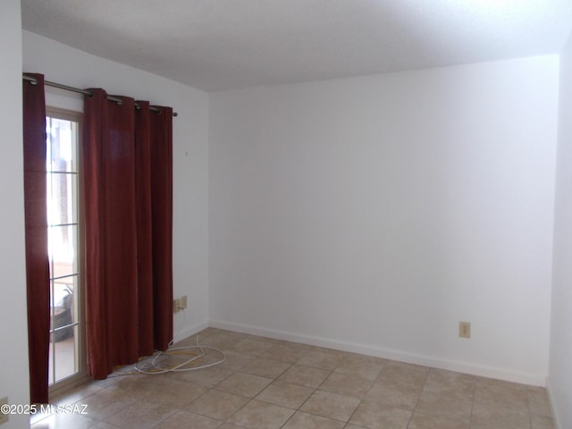 spare room featuring light tile patterned flooring and baseboards