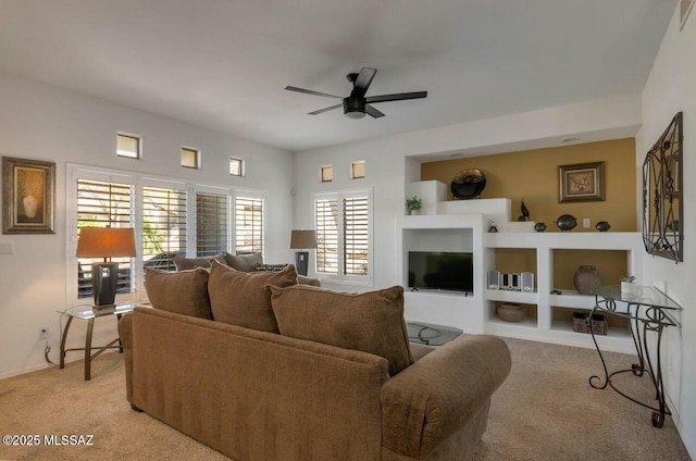 living area featuring a ceiling fan, built in features, and light colored carpet