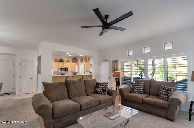 living area with ceiling fan, light tile patterned floors, and light colored carpet