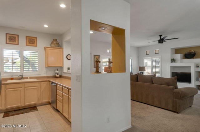 kitchen with ceiling fan, light brown cabinets, a sink, stainless steel dishwasher, and light tile patterned floors