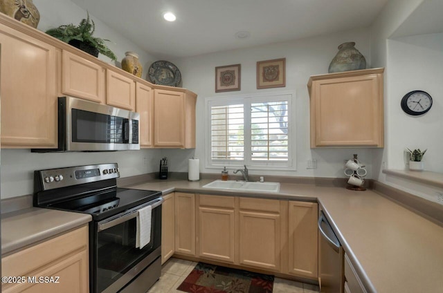 kitchen featuring light countertops, a sink, stainless steel appliances, and light brown cabinetry