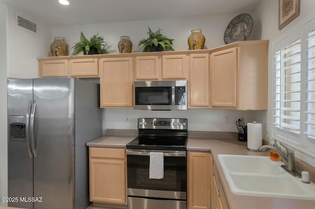 kitchen with light countertops, a sink, visible vents, light brown cabinets, and appliances with stainless steel finishes