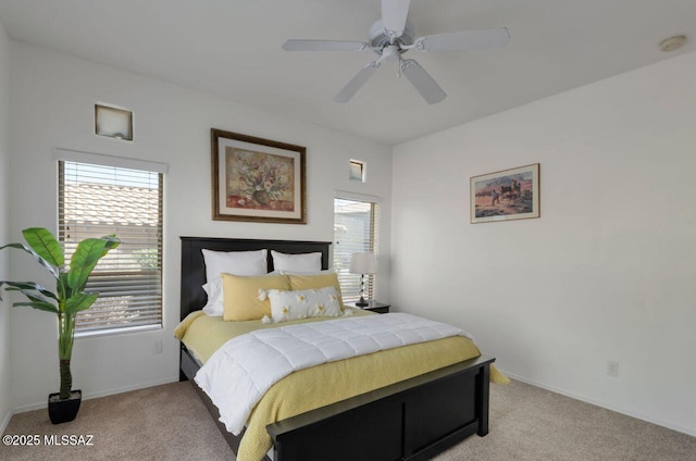 bedroom with multiple windows, light colored carpet, and a ceiling fan