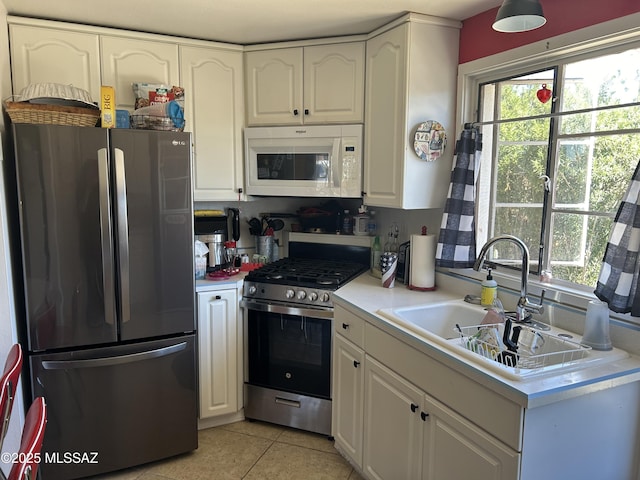 kitchen with a wealth of natural light, appliances with stainless steel finishes, a sink, and white cabinetry