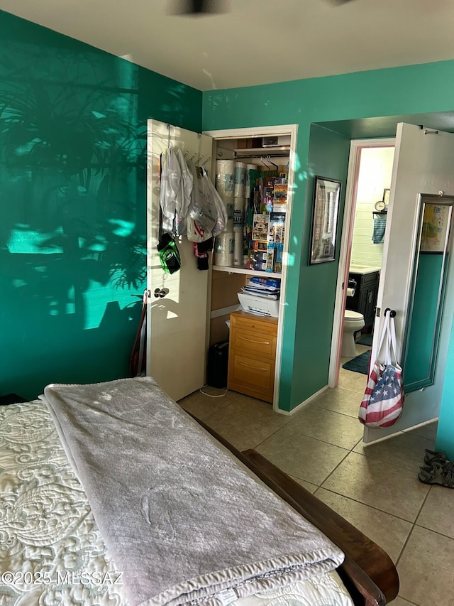 tiled bedroom with connected bathroom and a closet