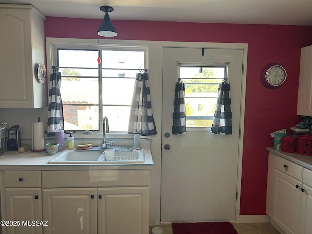 kitchen with white cabinets, light countertops, light tile patterned floors, and a sink