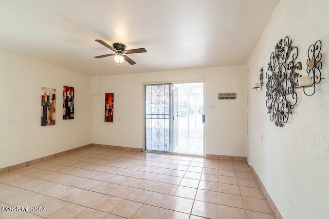 spare room featuring light tile patterned floors, baseboards, and a ceiling fan