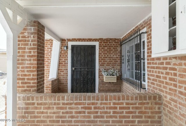 entrance to property featuring covered porch and brick siding