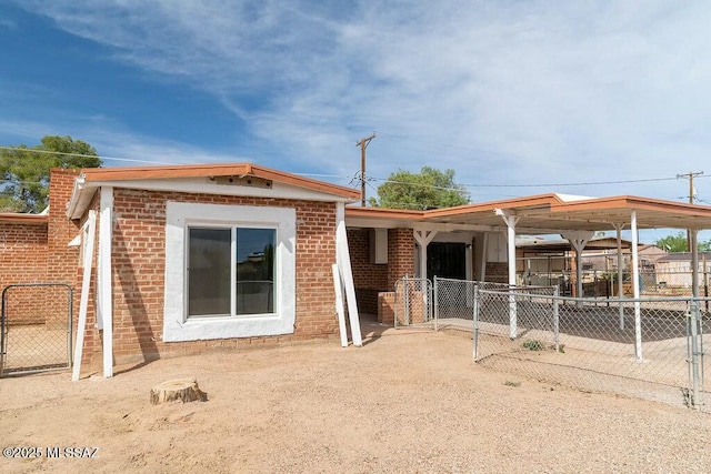 back of property with brick siding, fence, and a gate