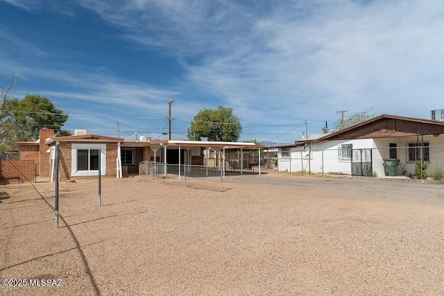 view of front of home featuring brick siding, an attached carport, and fence