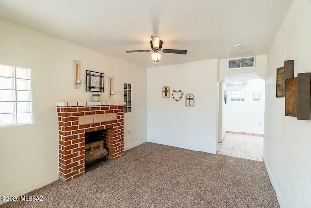 unfurnished living room featuring visible vents, a fireplace, a ceiling fan, arched walkways, and carpet floors