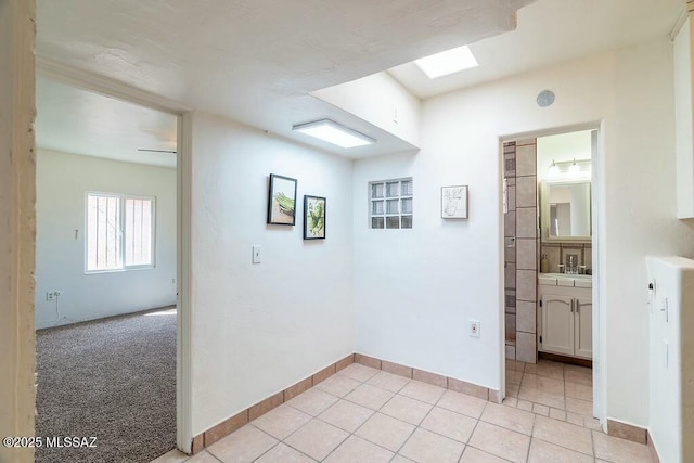 unfurnished room with light tile patterned flooring, baseboards, and light carpet