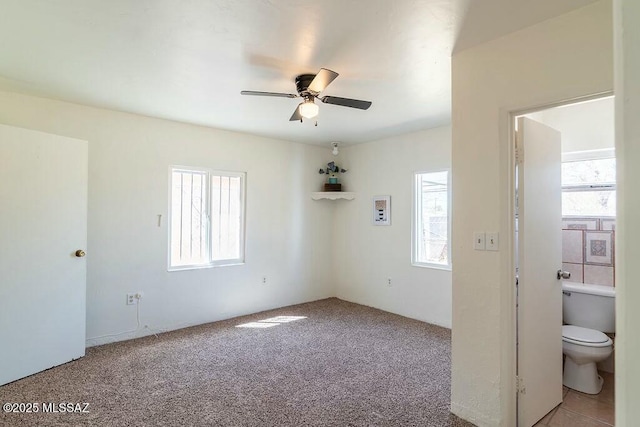 empty room with ceiling fan, a healthy amount of sunlight, and carpet