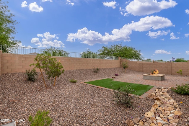 view of yard with a fire pit, a fenced backyard, and a patio area