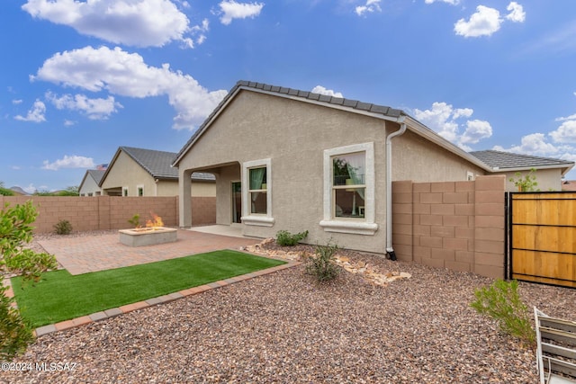 back of house featuring an outdoor fire pit, a fenced backyard, stucco siding, and a patio