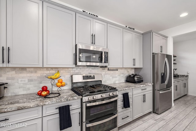 10150 S Rolling Water Dr, Vail, AZ 85641 - kitchen featuring appliances with stainless steel finishes, light stone counters, light wood-style flooring, and tasteful backsplash