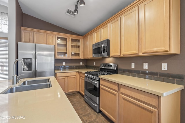 kitchen featuring vaulted ceiling, light countertops, a sink, appliances with stainless steel finishes, and light brown cabinets