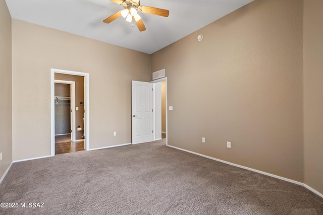 unfurnished bedroom with baseboards, visible vents, a spacious closet, and carpet