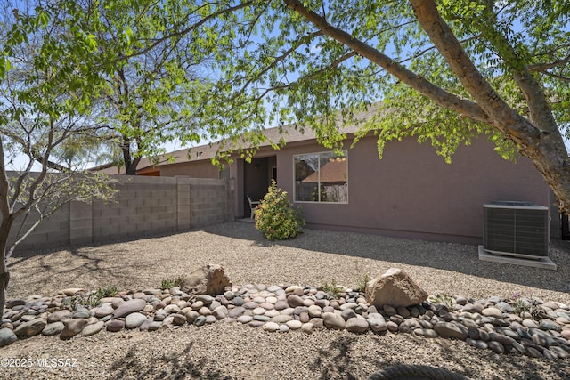 back of property featuring stucco siding, central AC, and fence