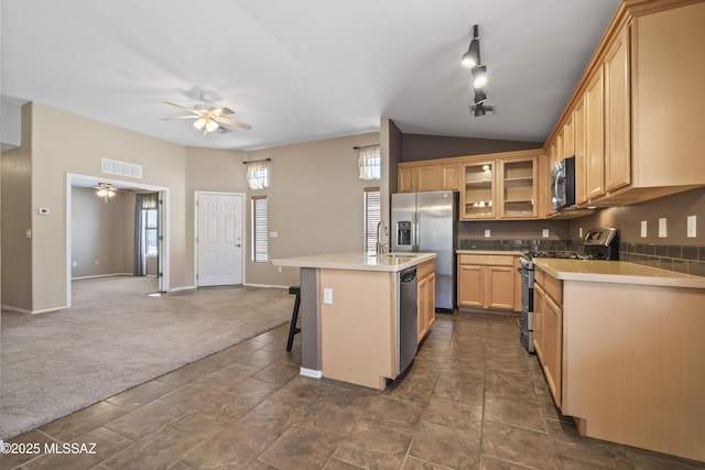 kitchen with vaulted ceiling, stainless steel appliances, ceiling fan, visible vents, and glass insert cabinets
