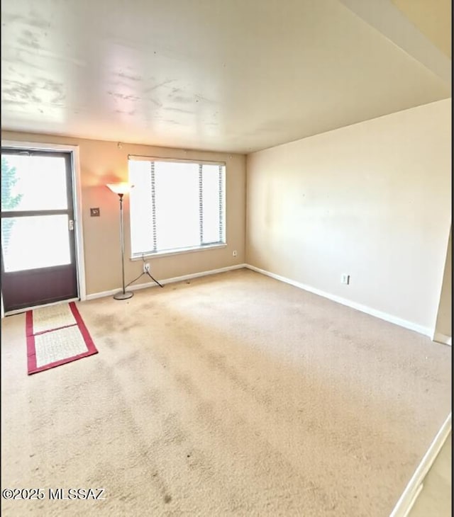 6902 E Calle Neptuno, Tucson, AZ 85710 - unfurnished living room featuring baseboards and light carpet