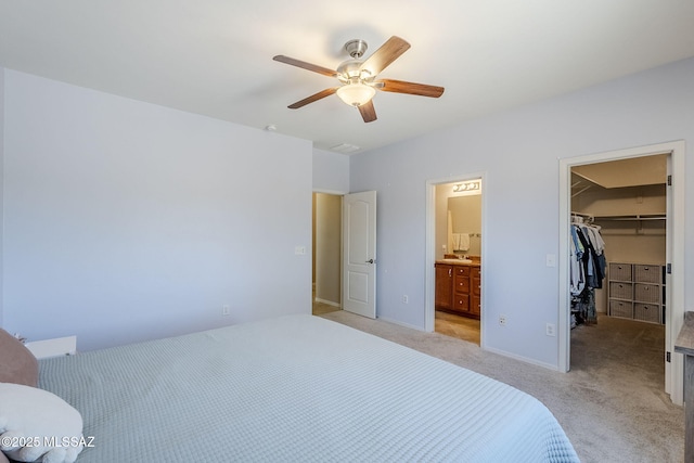unfurnished bedroom with a walk in closet, a ceiling fan, a closet, connected bathroom, and light carpet