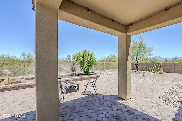 view of patio with a fenced backyard, a mountain view, and a fire pit