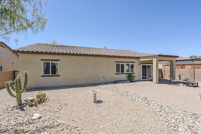 back of house featuring fence, a tile roof, a patio area, and stucco siding