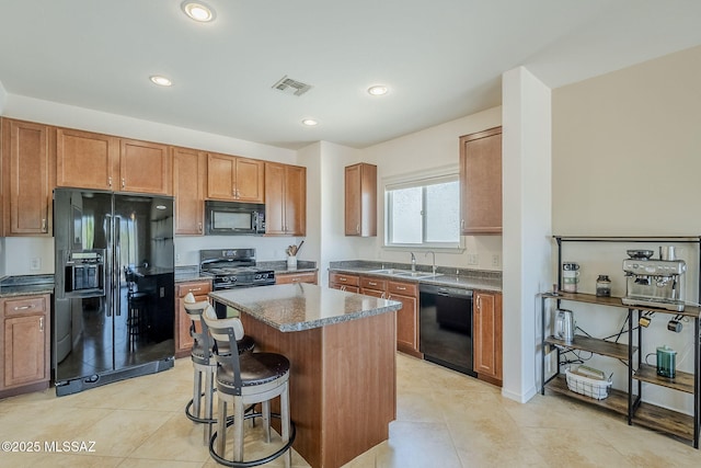 kitchen with a kitchen bar, a center island, recessed lighting, brown cabinets, and black appliances