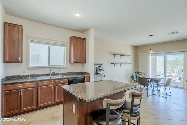 kitchen with a kitchen bar, a center island, a sink, light tile patterned floors, and black dishwasher
