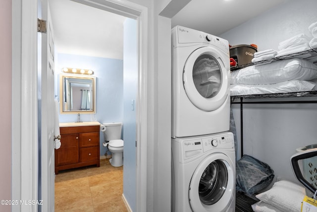 clothes washing area with stacked washing maching and dryer, light tile patterned floors, laundry area, and a sink