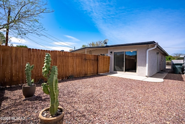 rear view of property featuring a patio, stucco siding, and fence